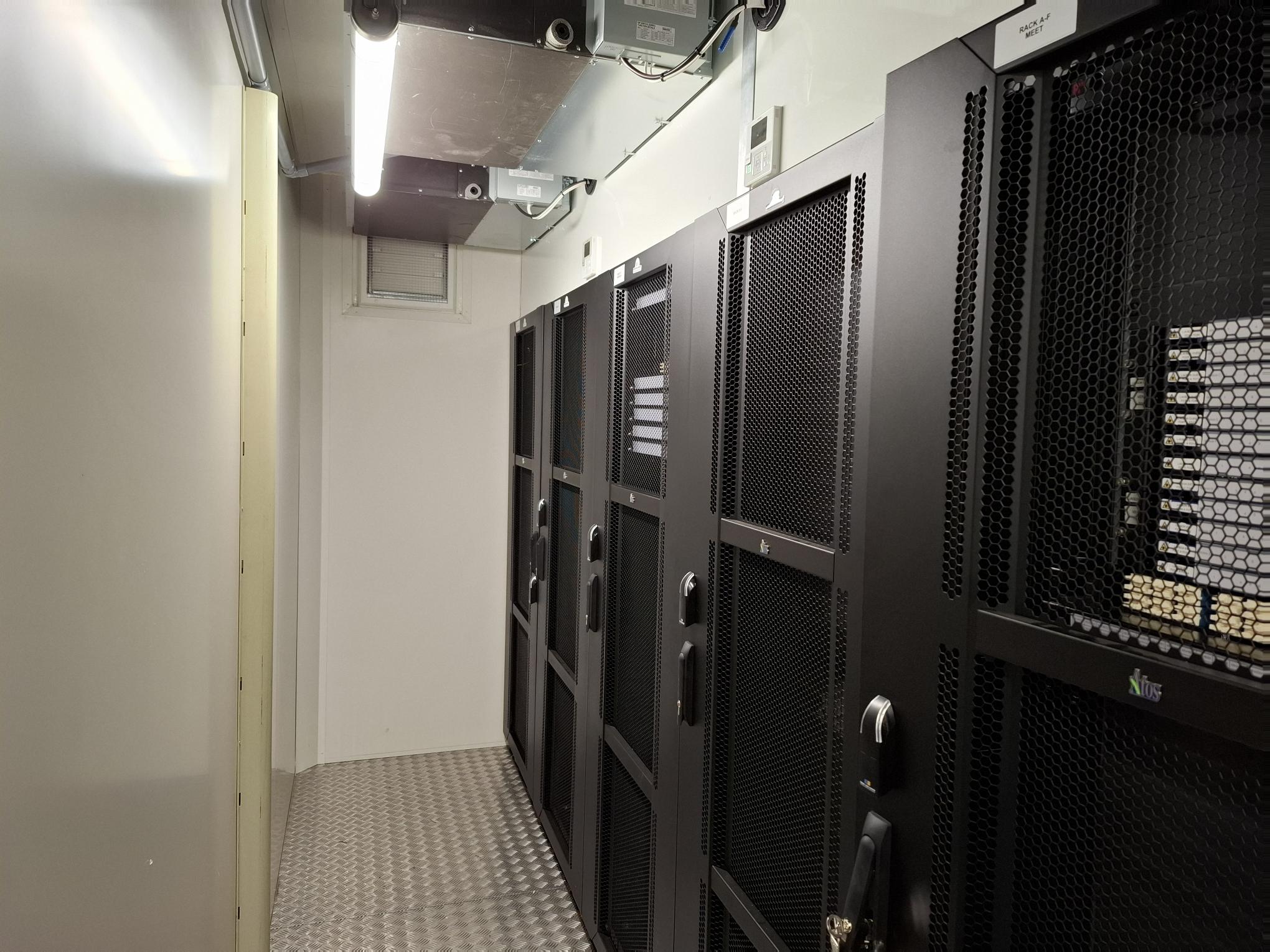 Salle de serveurs avec plusieurs armoires noires.