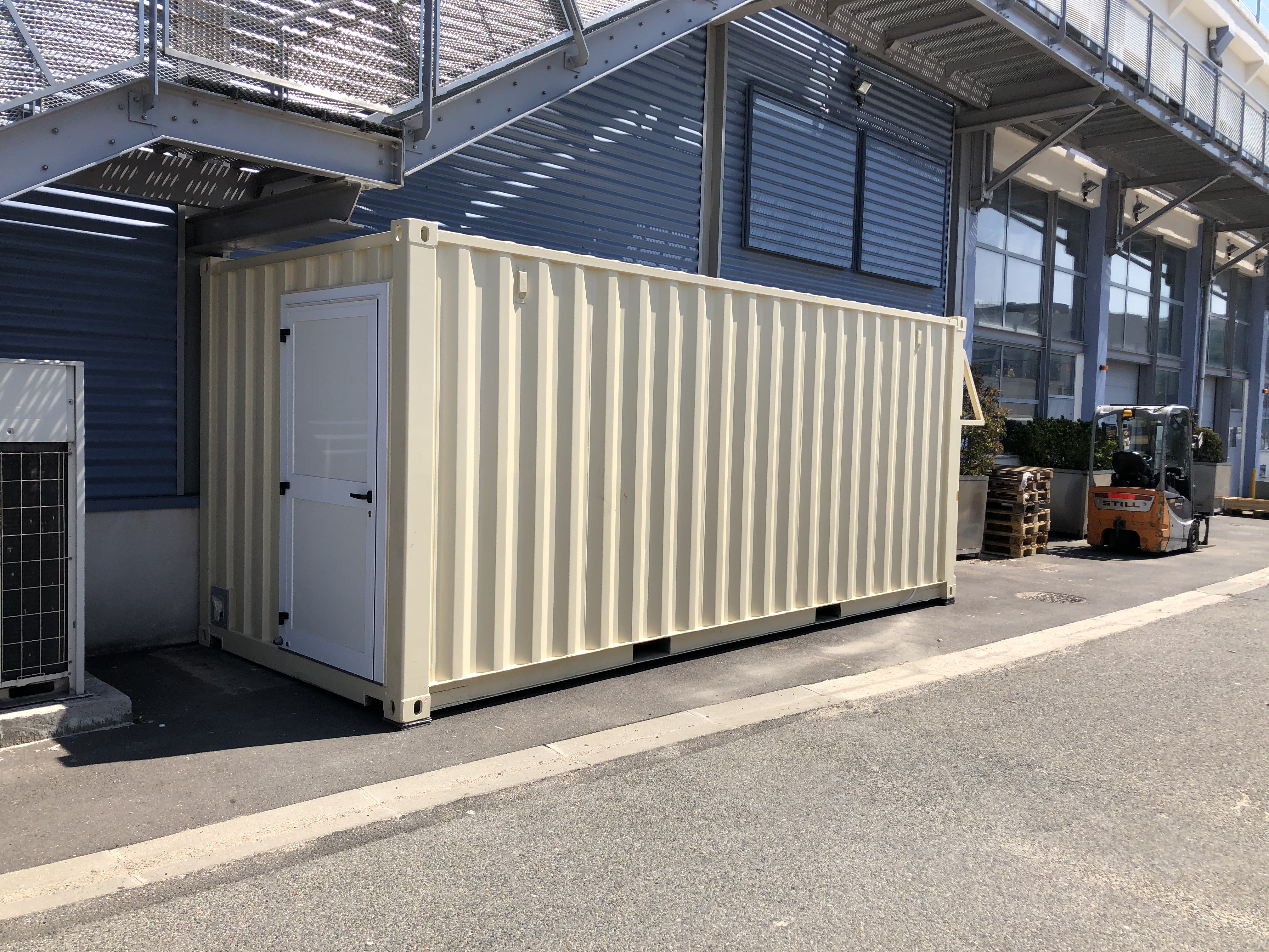 Conteneur de stockage devant un bâtiment industriel.